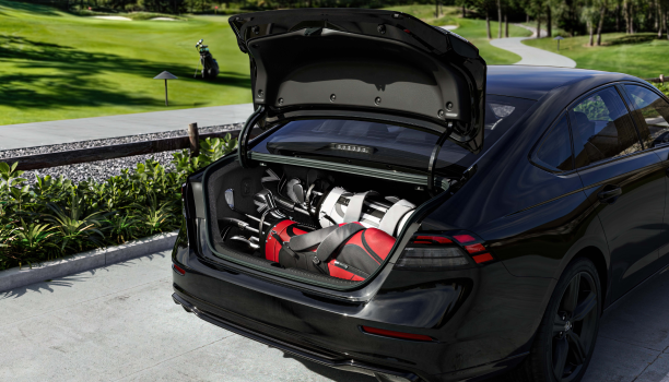 Wide view of the open trunk on a black Accord with two golf bags in it. 