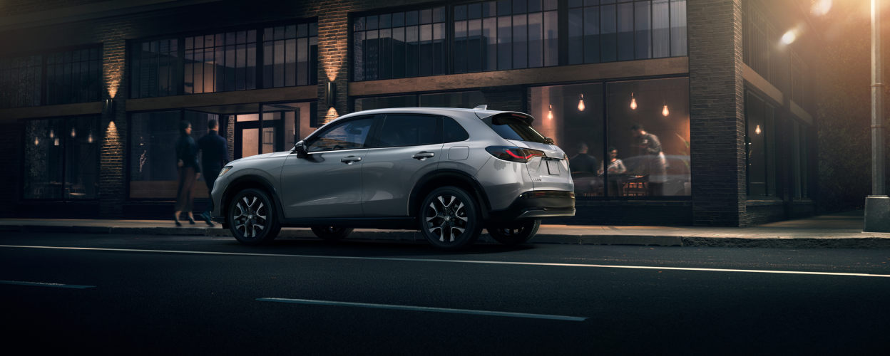 Sideview of grey HR-V parked outside a trendy brickwork restaurant at night.