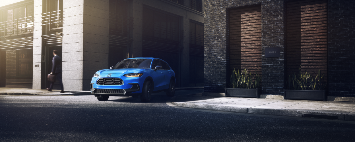 3/4 front view of blue HR-V pulling out of an alleyway in the city.