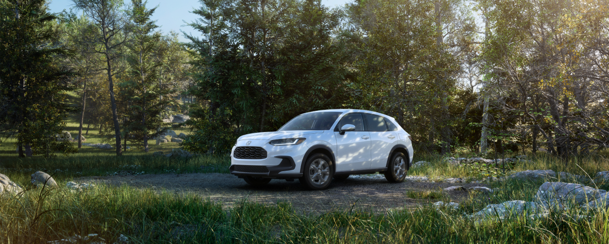 3/4 front side view of white HR-V parked in the forest. 