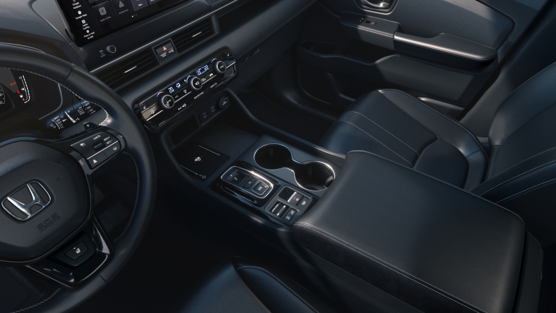 Driver’s side view of the steering wheel, dashboard, centre console and cup holders.