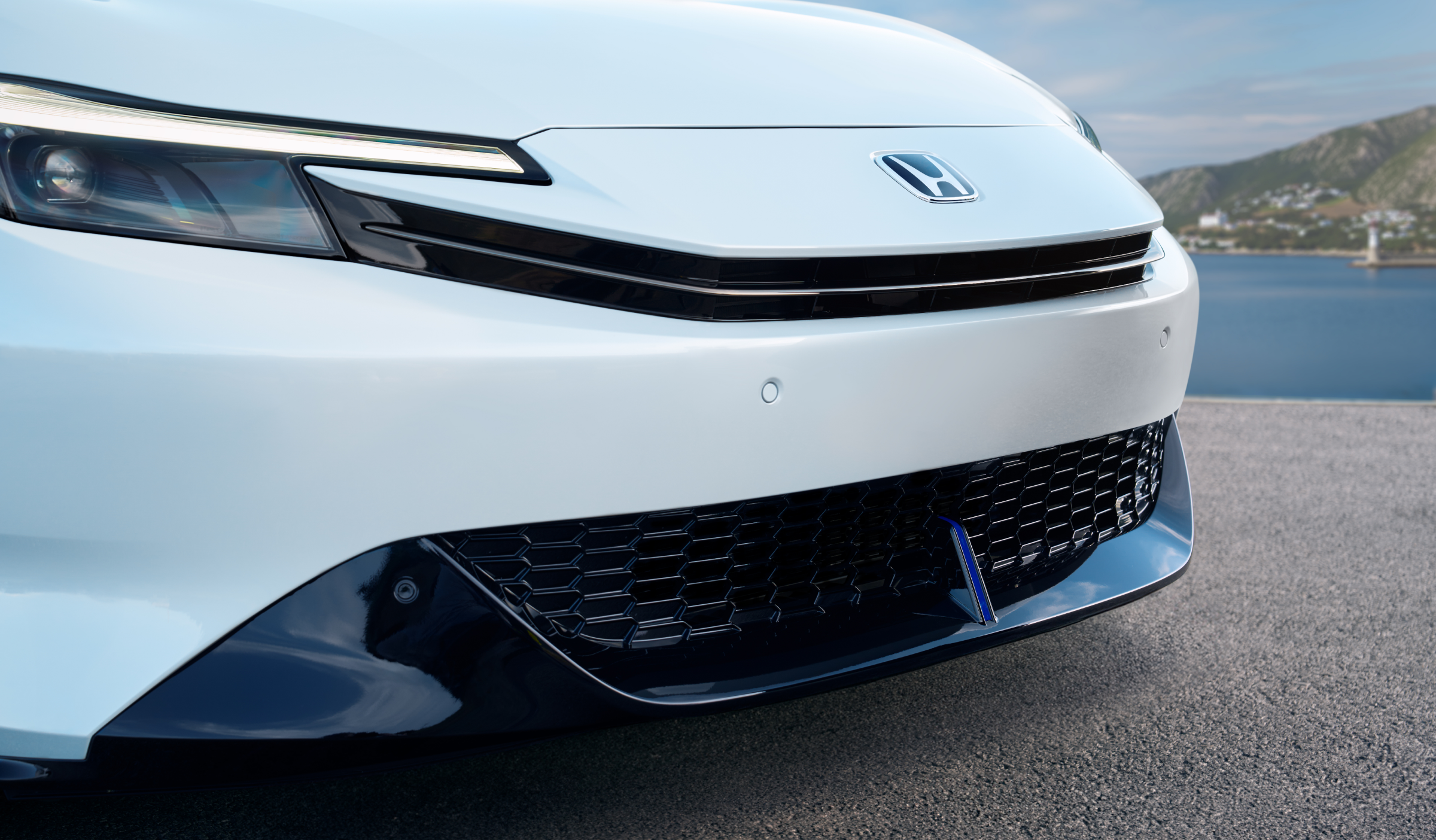 Closeup of a white Prelude's front fascia, showcasing its headlights and spoiler. 