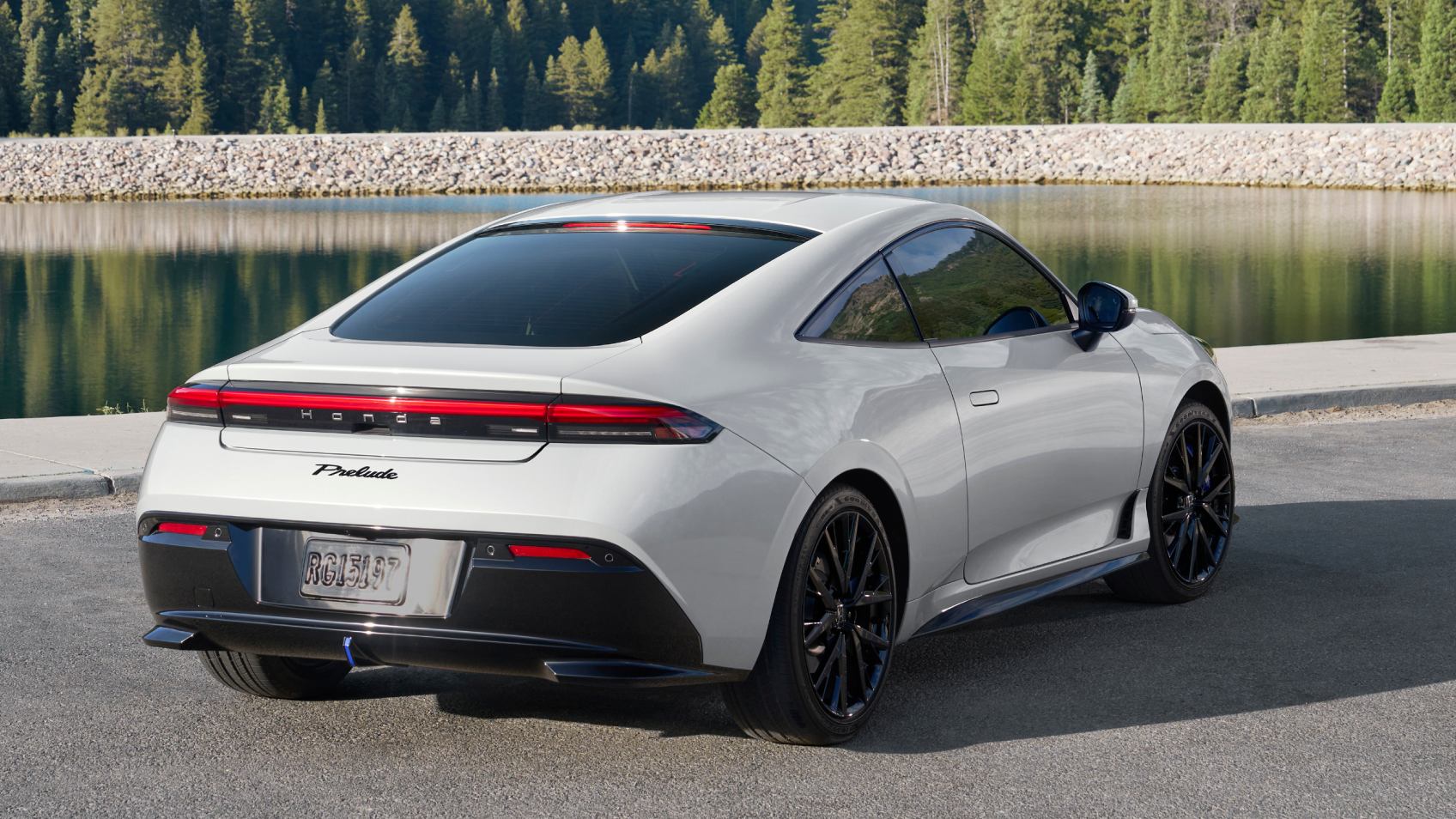Rear view of white Prelude parked against a backdrop of forest, rocks, and water.