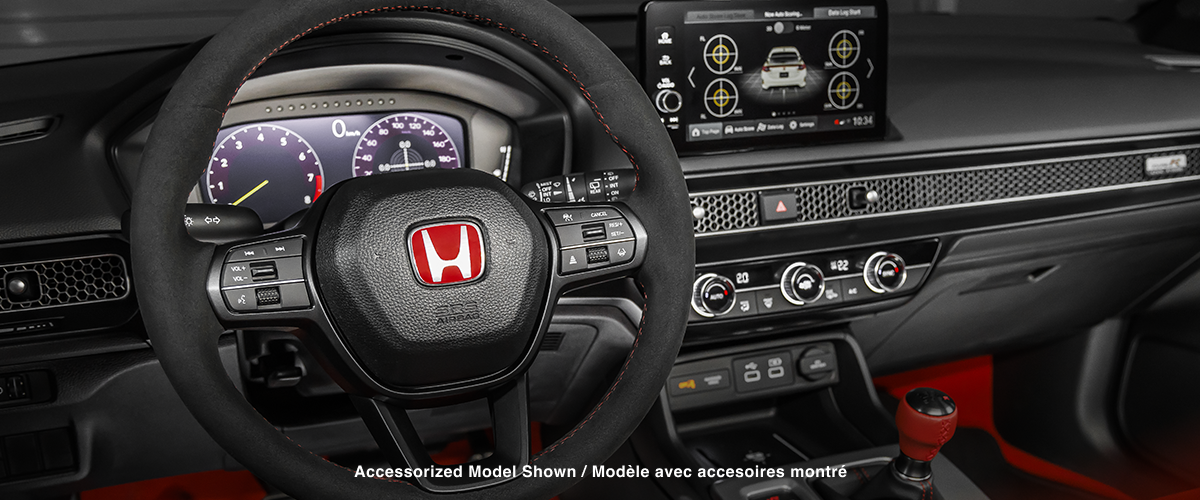 Medium closeup of steering wheel, dashboard, centre console, and gear shifter.