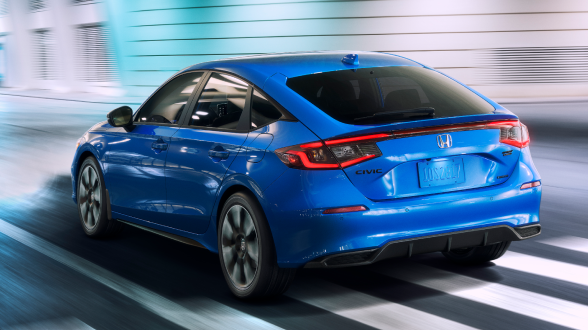 3/4 medium closeup of blue Hatchback driving on well-lit city street at night.