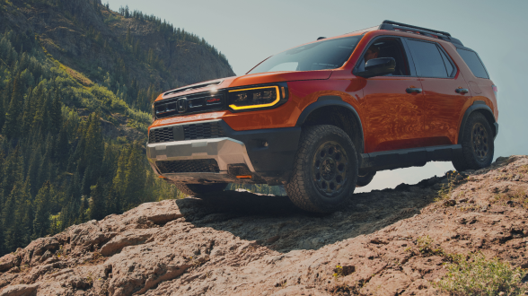 3/4 front view of orange Passport off-roading in desert.